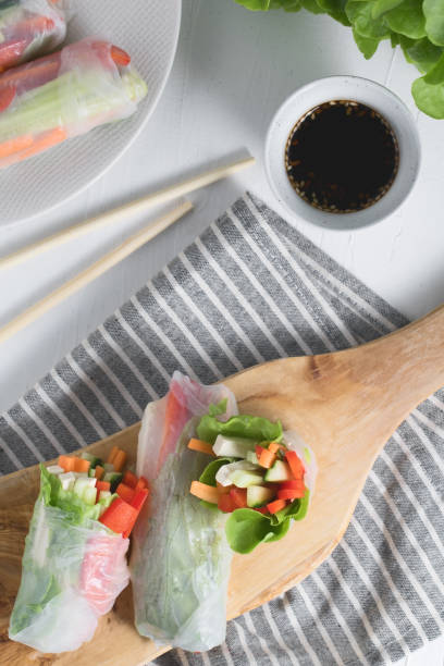 istock Asian fresh spring rolls. Raw cucumber, carrot, lettuce, bell pepper, tofu cheese inside rice paper. Top view. 951082494