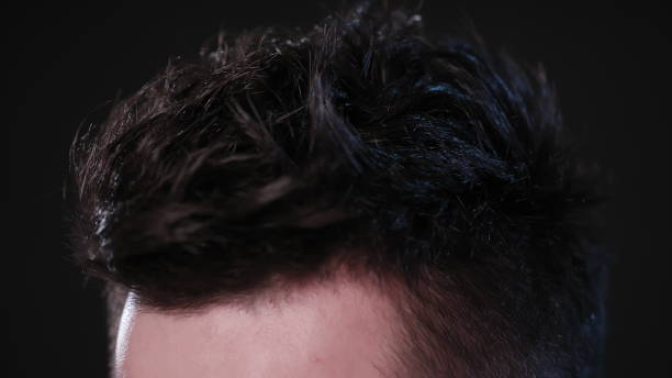 istock Man Touching his Hair Against a Black Background 951083526