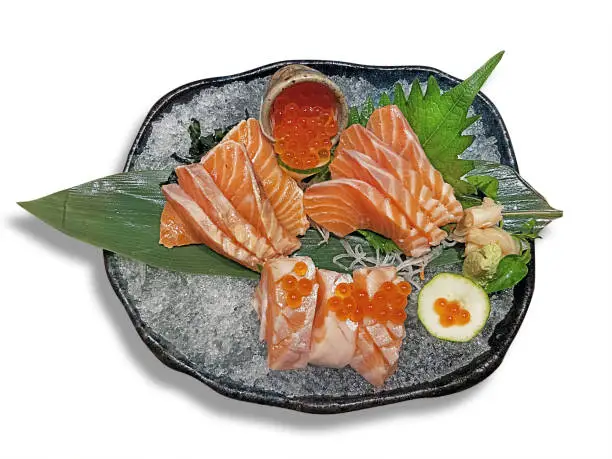 isolated on white with clipping path - salmon slice sashimi and salmon egg on ice for keep fresh served on black ceramic stone bowl photo take from top above view