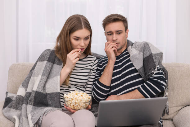 concentrado el hombre y la mujer viendo una película juntos - multi ethnic group couple sex women fotografías e imágenes de stock