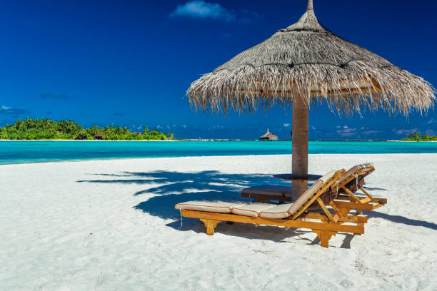 istock Two chairs and umbrella on a beach with shadow from palm tree 951087200