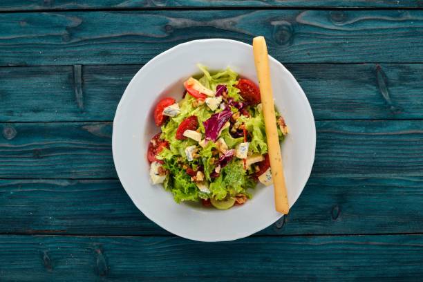 istock Salad with cheese, nuts and fresh vegetables. On a wooden background. Top view. Copy space for your text. 951088266