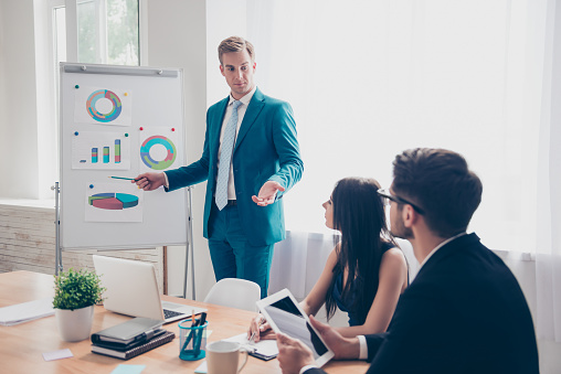 Young manager presenting whiteboard to his colleagues about financial growth