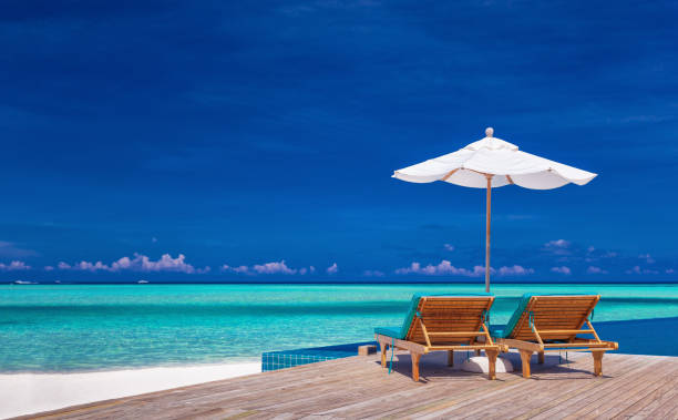 istock Deck chairs with umbrella overlooking infinity pool and lagoon 951090530