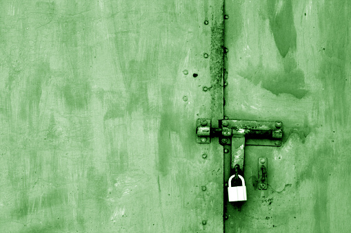 Old padlock on metal gate in green tone. Abstract background and texture.