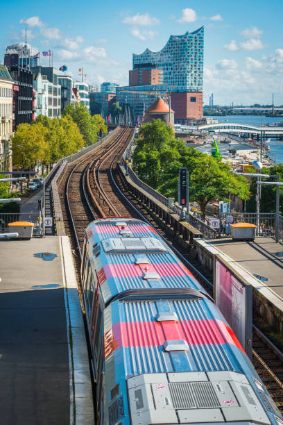 Barcelona, Spain - April 13, 2025: A red and white TMB train stands at a Barcelona metro station, photographed in profile along the track. Through the windows, passengers are visible standing and seated, while doors, bogies, and equipment along the roofline identify the rolling stock. The image conveys the routine of urban mobility: commuters during a stop, platform lighting reflecting on the carriage, and the compact layout typical of European rapid transit systems. References to Metro de Barcelona, public transport, and rush hour travel are present without centering on a specific event.