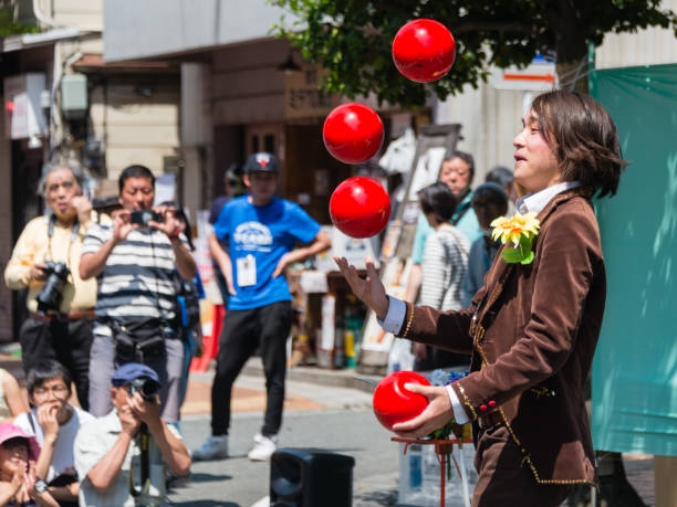 Yokohama, Japan - April 22, 2018: Street performer is juggling red balls on the Noge street in the International Street Performers Festival, which takes place on April 21 through 22 in 2018 in Yokohama, Japan. People are looking at the acrobatics.