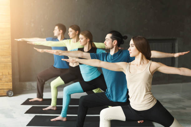 istock Young women and men in yoga class, doing stretching exercises 951104634