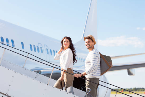 Couple leaving for a vacation Beautiful young couple boarding a flight. Man and woman going on a holiday. flight of steps stock pictures, royalty-free photos & images