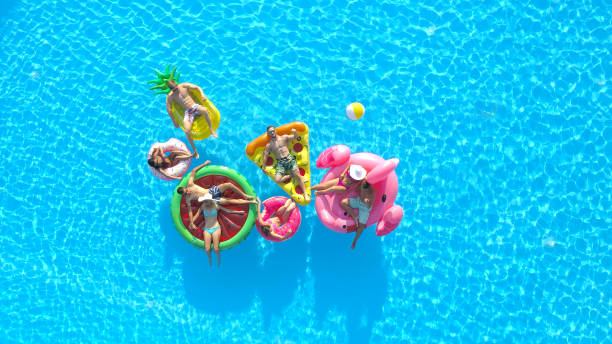 aerial: cheerful fit people on summer vacation enjoying on fun inflatable floats - bikini summer vacations looking down imagens e fotografias de stock