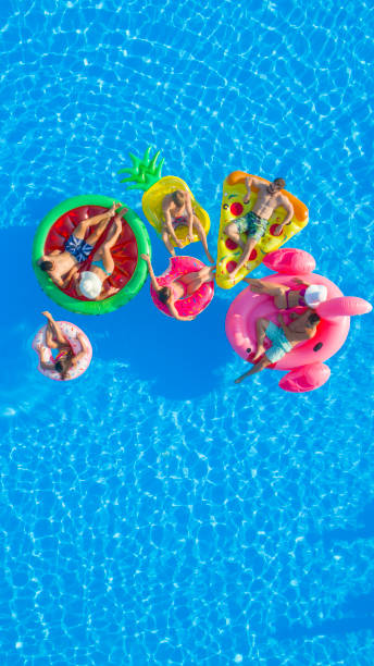 istock AERIAL People chilling on flamingo, pizza, pineapple, watermelon, doughnut float 951105770