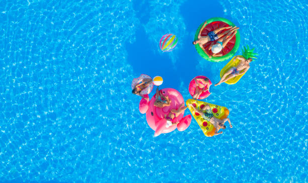 antena: amigos joven felizes jugando voleibol de agua en diversión floaties en piscina - floating on water swimming pool men water fotografías e imágenes de stock