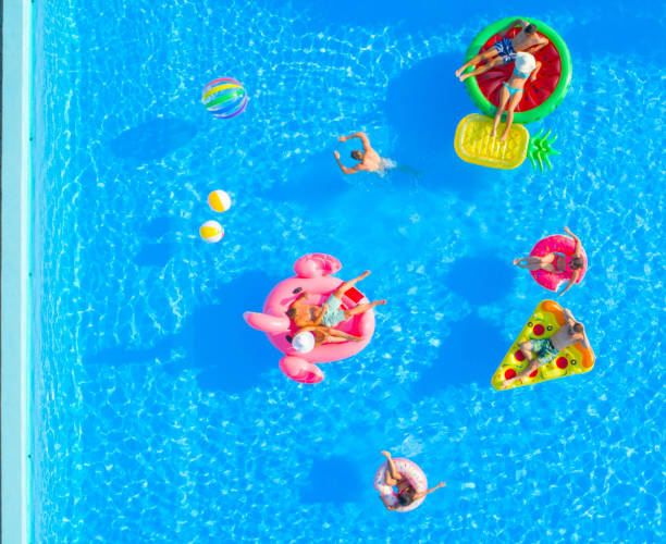istock AERIAL TOP DOWN: Cheerful young friends enjoying fun inflatable floaties in pool 951105802