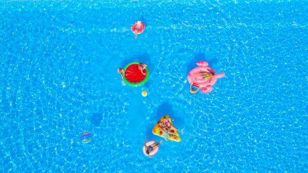 istock AERIAL: Playful young friends having a watergun fight on fun floaties in pool 951105878