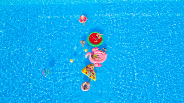 istock AERIAL: Cheerful young friends having a watergun fight on fun floaties in pool 951105888