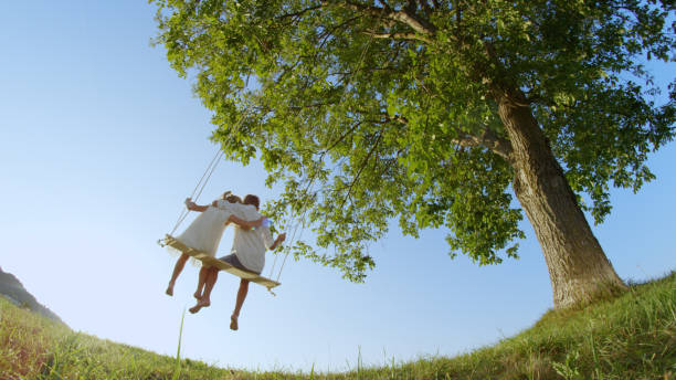 istock LOW ANGLE VIEW Barefoot boy and girl embracing each other on a swing under tree 951105936