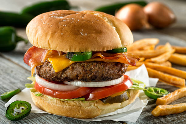 Bacon Cheddar Jalapeno Burger A delicious burger with bacon, cheddar, jalapeno pepper, tomato, onion, pickle and lettuce with french fries. char grilled photos stock pictures, royalty-free photos & images