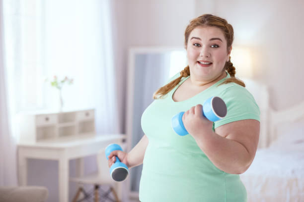 istock Overjoyed young woman holding dumbbells 951127050