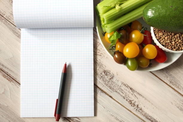 istock Diet plan notebook and vegetables on the wooden table. 951128656