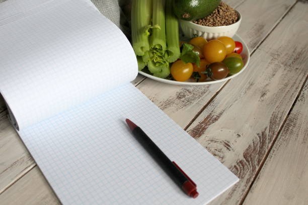 istock Diet plan notebook and vegetables on the wooden table. 951128880