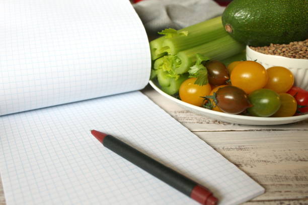 istock Diet plan notebook and vegetables on the wooden table. 951128964