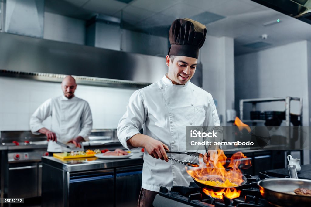 Mastering new culinary heights Shot of two young cooks preparing food in the kitchen Chef Stock Photo