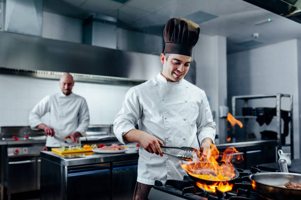 Mastering new culinary heights Shot of two young cooks preparing food in the kitchen balkans photos stock pictures, royalty-free photos & images