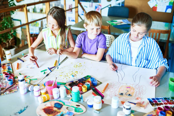 istock Three Schoolchildren Painting Pictures 951133672