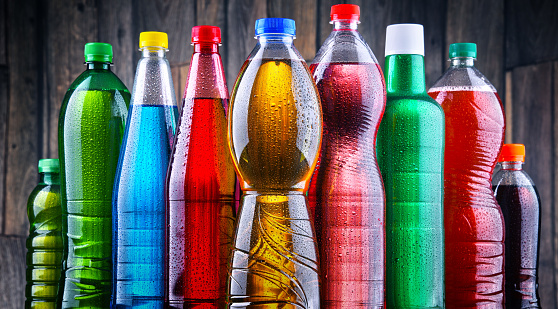 Plastic bottles of assorted carbonated soft drinks in variety of colors.