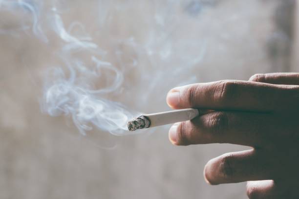 fumar tabaco de cigarrillos en la mano con un enfoque suave. concepto de dejar de fumar cigarrillos es peligroso para la salud. - cenicero fotografías e imágenes de stock