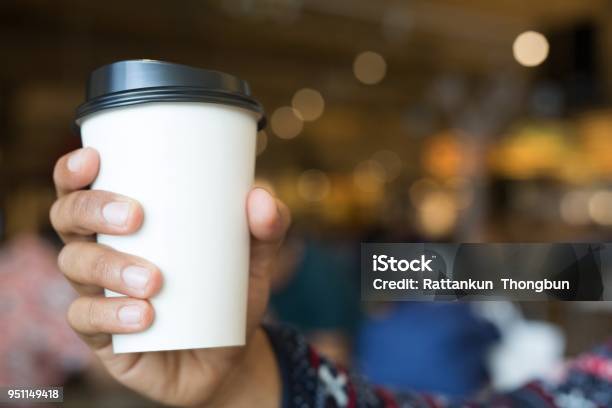 Young Man Hand Holding Paper Cup Of Take Away Drinking Coffee Hot On Cafe Coffee Shop Stock Photo - Download Image Now