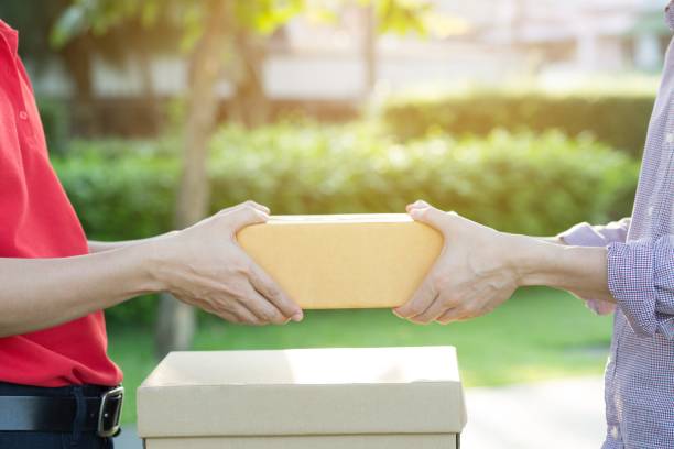 istock parcel delivery man of a package through a service. and close up hand customer accepting a delivery of boxes from delivery man postal. 951149898