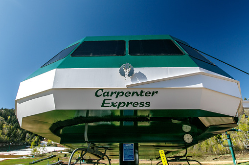 Park City, UT, May 12, 2017: Sun shines of the Carpenter Express lift at the base of the mountain of Deer Valley ski resort. The structure is decoraed with the resort logo.