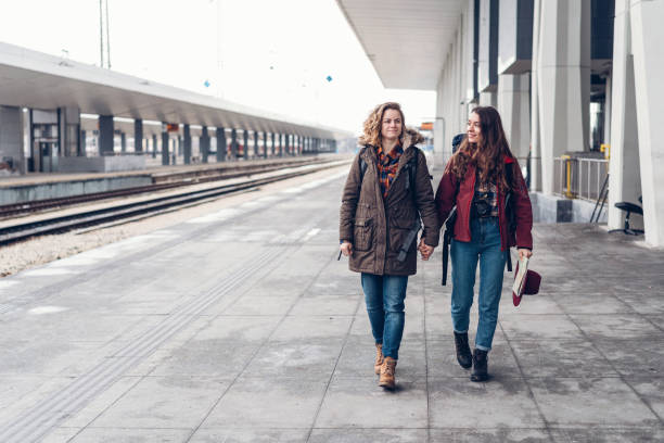 istock Women holding hands and walking on the railway station platform 951154496