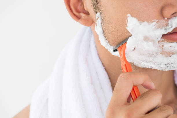 istock Handsome young man with foam on his face is beard shaving. 951155378