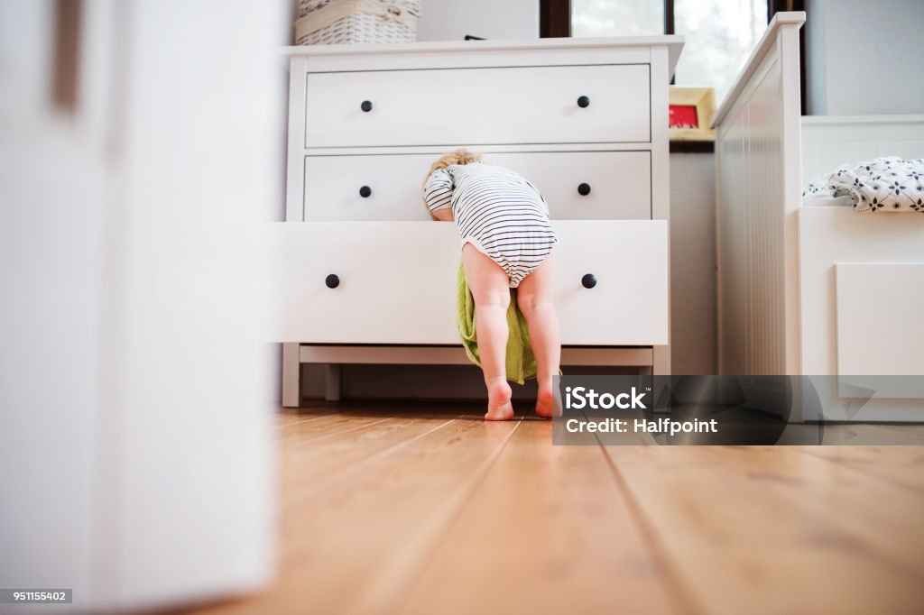 Toddler boy in a dangerous situation at home. Little toddler boy opening a drawer. Domestic accident. Dangerous situation at home. Rear view. Child Stock Photo