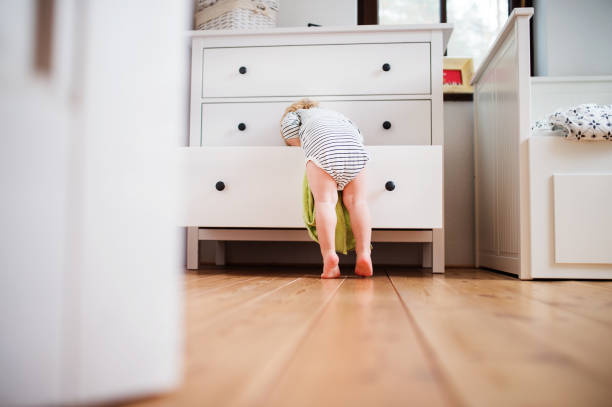 Toddler boy in a dangerous situation at home. Little toddler boy opening a drawer. Domestic accident. Dangerous situation at home. Rear view. dresser stock pictures, royalty-free photos & images