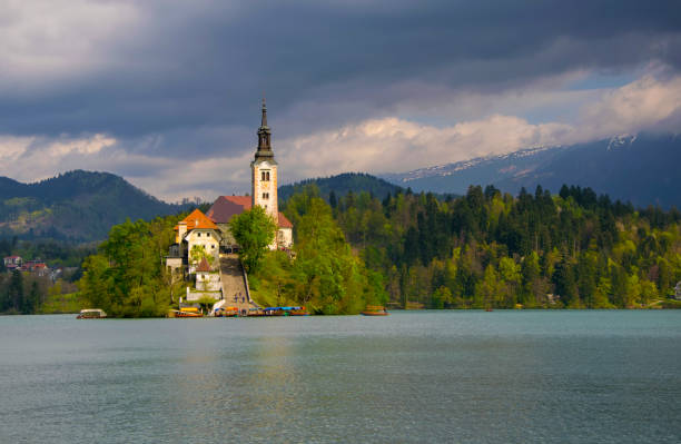 istock Bled lake and pilgrimage church in sunlit with dark background 951159292