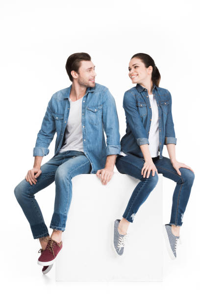 istock happy couple looking at each other and sitting on white cube, isolated on white 951162832