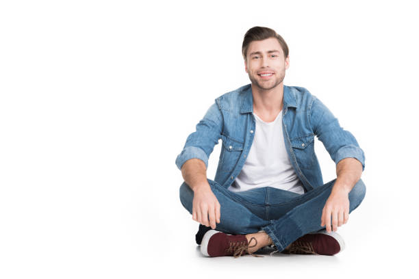 istock young smiling man sitting in jeans looking at camera, isolated on white 951167256