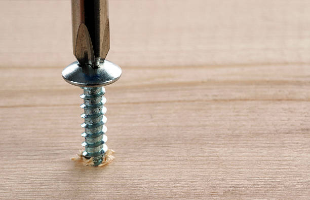 Screw & Screwdriver with blurred wood background with space for copy