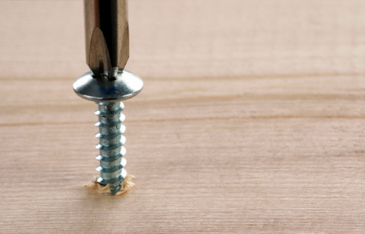 Screw & Screwdriver with blurred wood background with space for copy