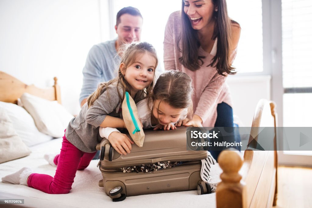 Young family with two children packing for holiday. Portrait of a young happy family with two children packing for holiday at home. Family Stock Photo