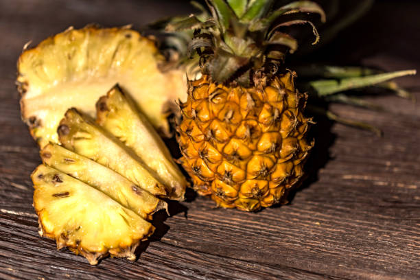 istock Pineapples on a dark wooden background 951172956