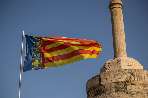 Valencian flag on top of the Torres de Serranos blowing in the wind at sunset