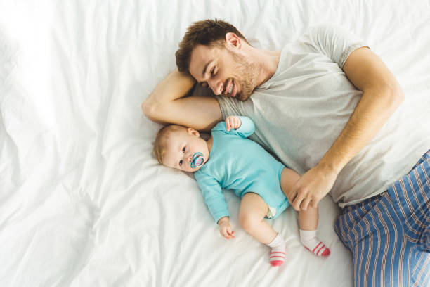 istock High angle view of young father laying in bed with infant daughter 951176708