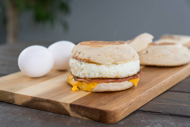 Canadian Bacon, Egg and Cheese Breakfast Sandwich Canadian Bacon, egg and cheese breakfast sandwich with english muffin on cutting board english muffin stock pictures, royalty-free photos & images