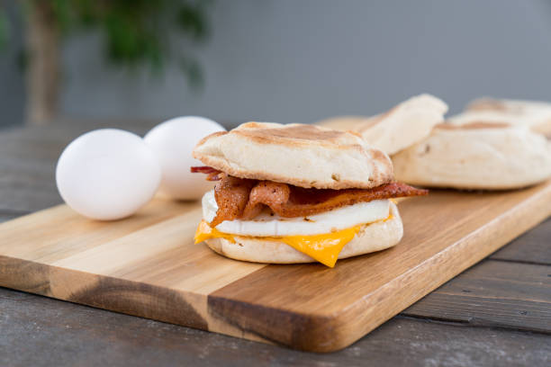 Bacon, Egg and Cheese Breakfast Sandwich Bacon, egg and cheese breakfast sandwich with english muffin on cutting board biscuit quick bread stock pictures, royalty-free photos & images