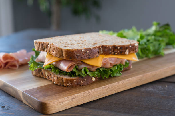 Fresh Ham and Cheese Sandwich Fresh Ham and Cheese Sandwich on Whole Wheat Bread on Cutting Board ham and cheese sandwich stock pictures, royalty-free photos & images