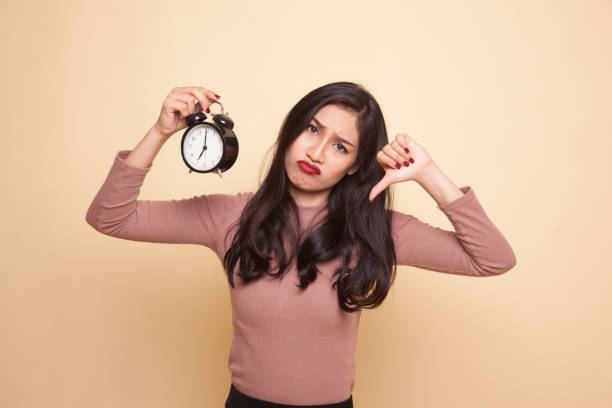 istock Young Asian woman thumbs down with a clock. 951185922